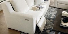 a white couch sitting on top of a wooden floor next to a table and chair