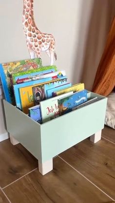 a toy giraffe standing on top of a wooden box filled with books