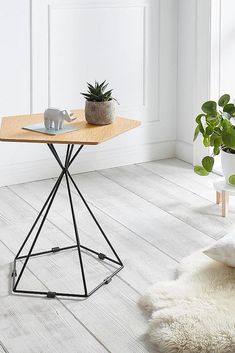 a small table with a plant on top in a room next to a white wall