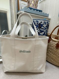 a white tote bag sitting on top of a counter next to a basket and mirror