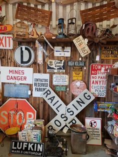 many signs are hanging on the wall next to a trash can and other junk items