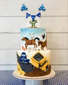 a three tiered cake with cars, trucks and horses on it's side