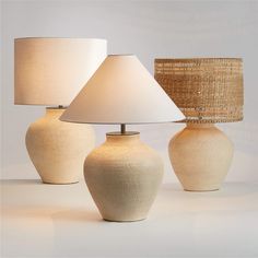 three white vases with lamps on top of them