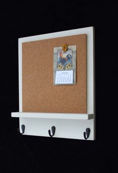 a cork board mounted to the side of a wall with magnets and hooks on it