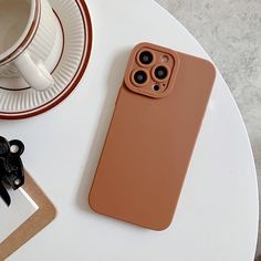 an iphone case sitting on top of a table next to a cup and saucer