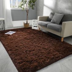 a living room area with a couch, chair and rug on the floor in front of a window