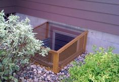 a wooden box sitting in the middle of some rocks next to a tree and bushes