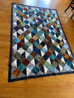 a multicolored quilt is on the floor next to a wooden chair and table