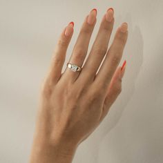 a woman's hand with red nail polish and a ring on her finger, against a white background