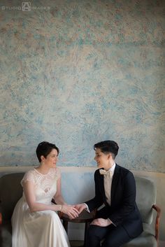 a man and woman sitting on a couch next to each other in front of a wall