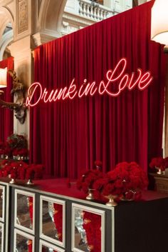 a red curtain with the word drunk in love written on it and flowers all around