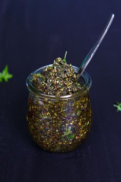 a jar filled with some sort of food on top of a black table next to green leaves