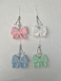 three small crocheted bows hang from silver earwires on a white background