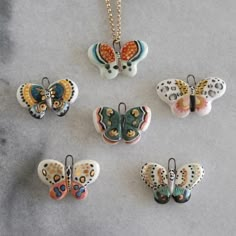 six butterfly shaped pendants on a silver chain, all with different colors and designs