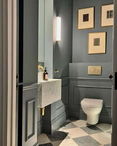 a white toilet sitting in a bathroom next to a wall mounted light above it's tank