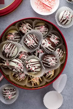 a red bowl filled with chocolate covered candies and sprinkles next to white plates