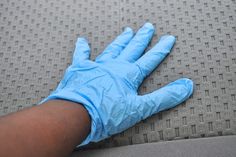 a person's hand with blue gloves on it laying on a gray fabric surface