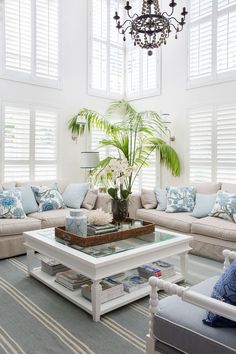 a living room filled with lots of furniture and a chandelier hanging from the ceiling