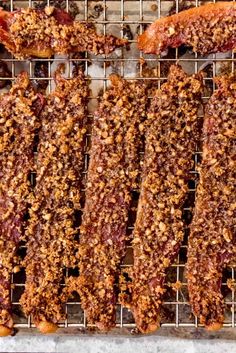 several pieces of meat sitting on top of a metal grill grates covered in toppings