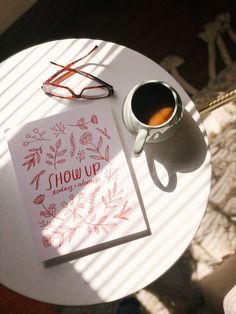 a cup of coffee sitting on top of a table next to a book