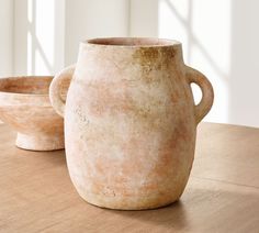 two large vases sitting on top of a wooden table