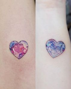 two small heart tattoos on the wrist, one with a pink and blue diamond in it