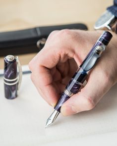 a person holding a pen and writing on a piece of paper