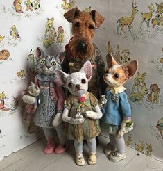 a group of stuffed animals standing next to each other in front of a wallpapered background