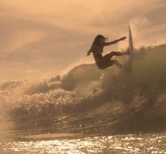 a person riding a surf board on a wave in the ocean with sun shining behind them