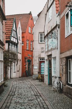 an old cobblestone street with buildings and bicycles parked on the side walk in front of it