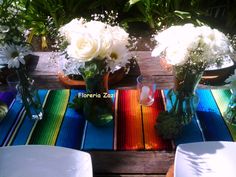 three vases filled with white flowers sitting on top of a table next to chairs