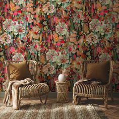 two chairs sitting in front of a wall with flowers on it