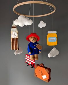 a teddy bear in a red hat and blue coat is hanging from a wooden mobile