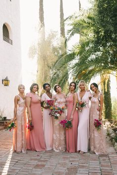 a group of women standing next to each other on a brick floored walkway with palm trees in the background