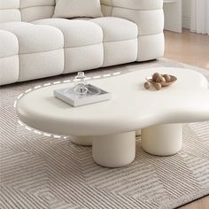 a white coffee table sitting on top of a rug in front of a large couch