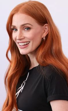 a woman with long red hair smiling at the camera