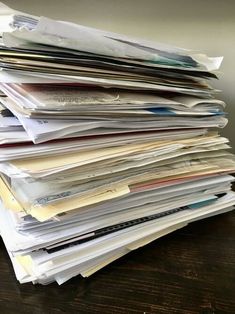 a stack of papers sitting on top of a wooden table