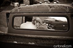 a woman sitting in the back seat of an old pickup truck looking at her reflection