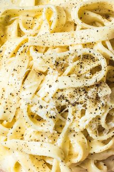 a close up view of some noodles with seasoning on top, and black pepper sprinkled on the side