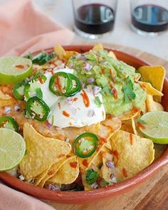 a bowl filled with nachos and lime wedges