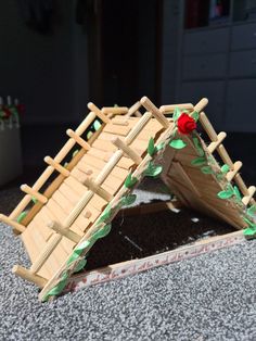 a small wooden structure made to look like a house with leaves and flowers on it