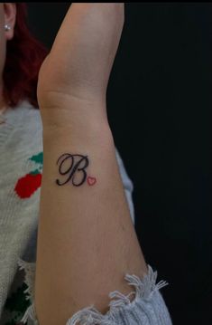 a woman's arm with a tattoo on it that has the letter b and heart