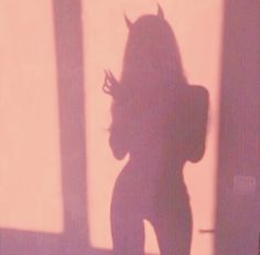 the shadow of a woman standing in front of a window holding a cell phone to her ear