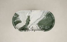 an oval marble tray with green and white designs on the edges, hanging from a wall