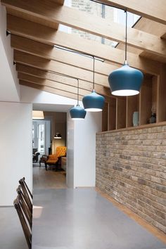 an empty room with blue lamps hanging from the ceiling and wooden beams on the walls