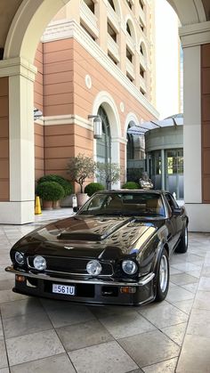 a black car parked in front of a building with an arched doorway on the side