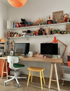 a desk with two computers on top of it and shelves above the desk behind it