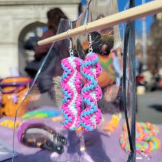 pink, blue and white beaded earrings on display in front of a window at an outdoor fair