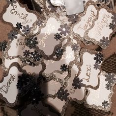 some silver and white tags with black flowers on them, sitting on a brown surface