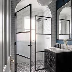 a bathroom with black and white tile flooring and walls, along with a walk in shower